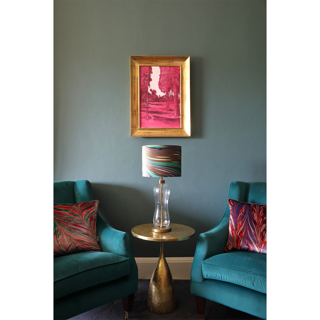 Velvet cushions on chairs with lamp shade on round table in the middle