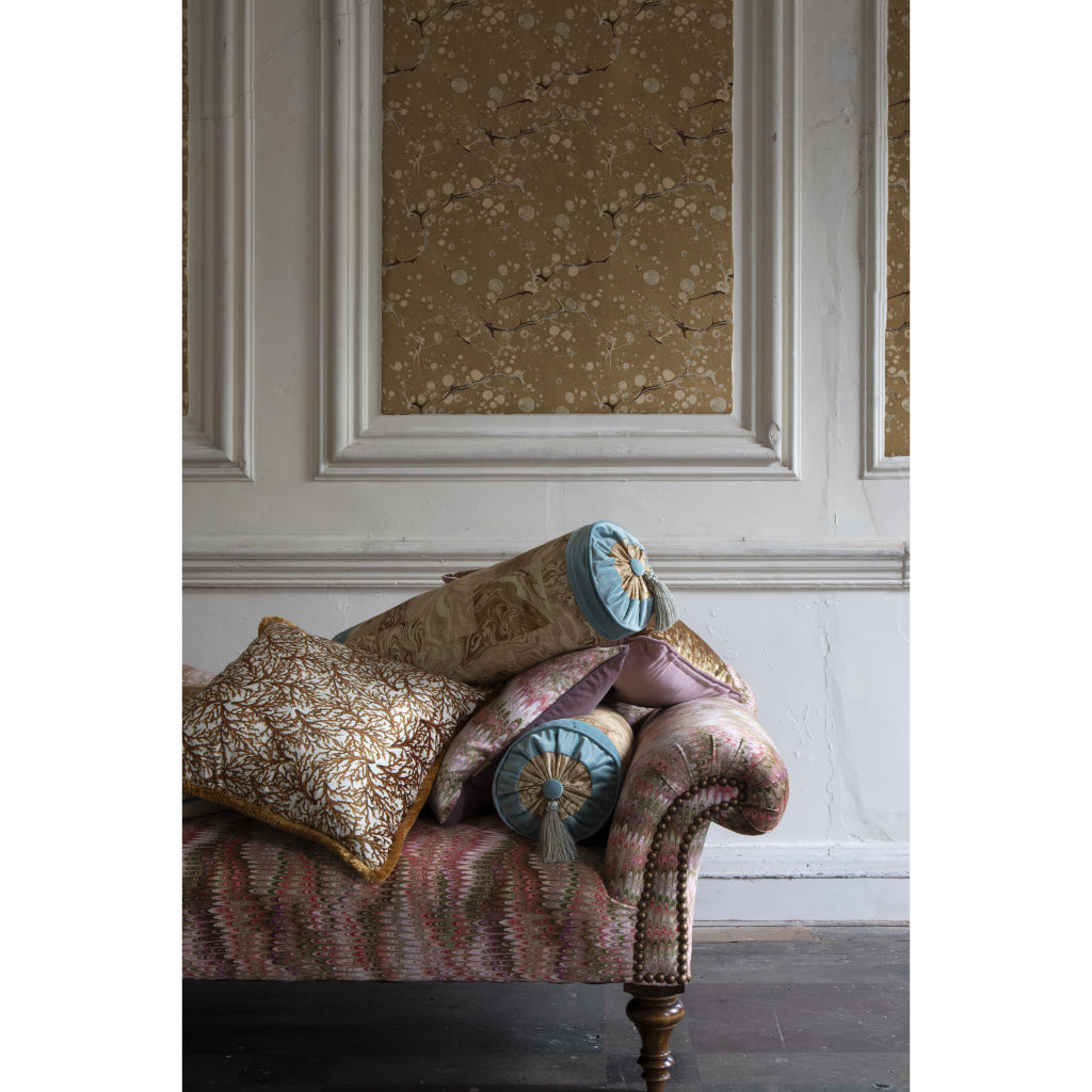 Decorative pillows on a patterned sofa with a textured wall in the background