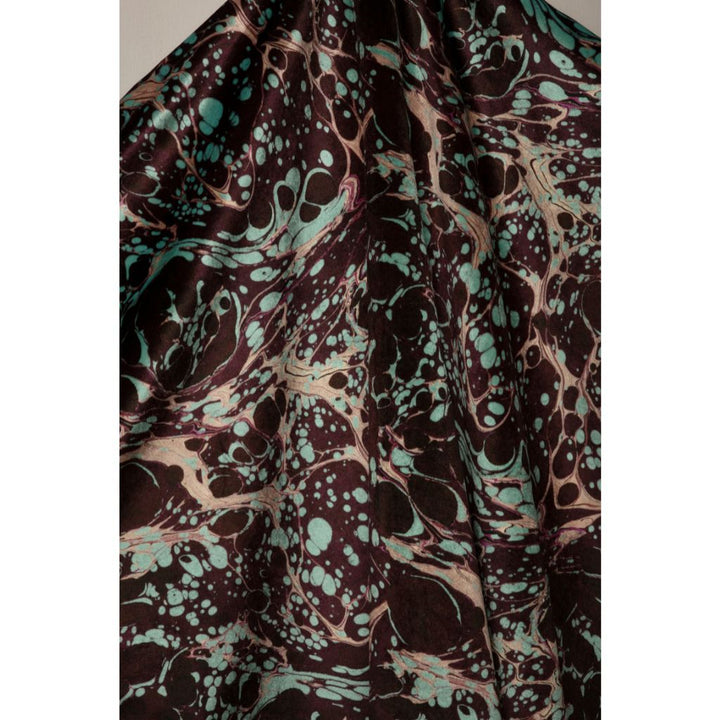 A close-up of draped fabric with an abstract marbled pattern in dark brown, black, teal, and beige.