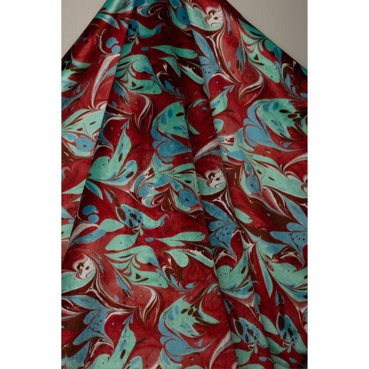 A close-up of draped fabric with an abstract marbled pattern in deep red, turquoise blue, mint green, and white.