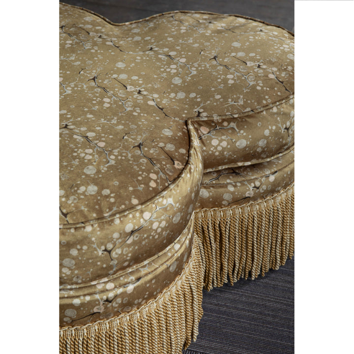 Pouffe upholstered in gold and brown marbled patterned fabric 