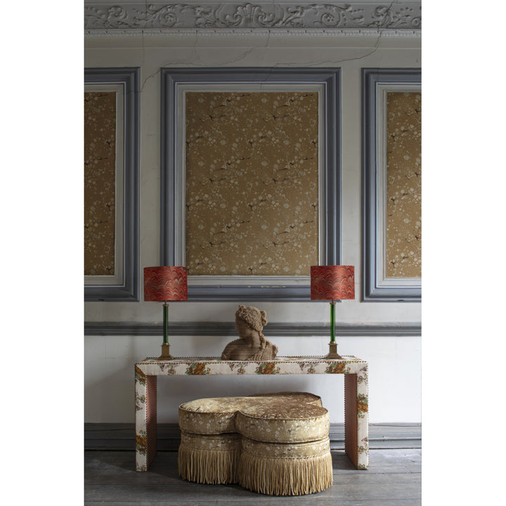 Decorative room setting with a console table, ottomans, and framed artwork on a wall.