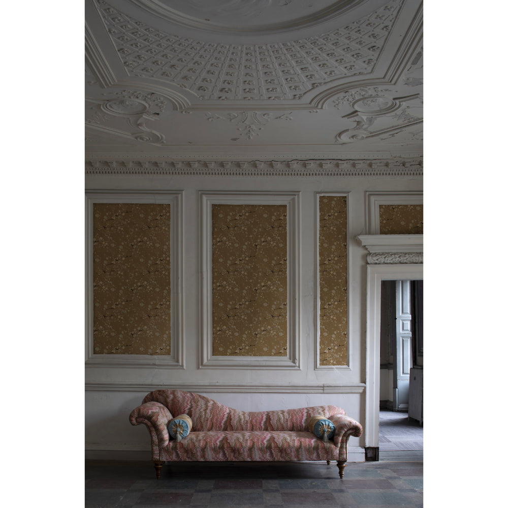 Vintage-style room with ornate ceiling and gold wallpaper, featuring a patterned sofa.