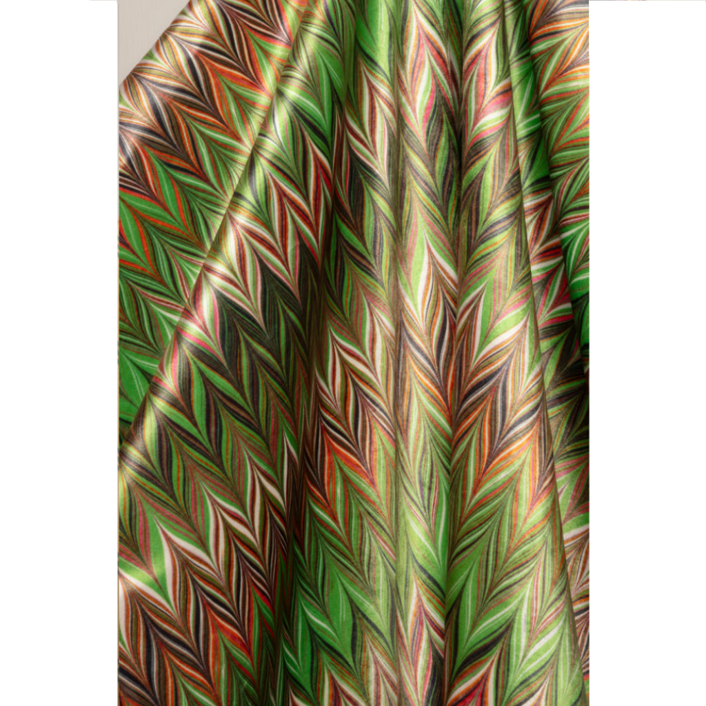 A close-up of draped fabric with a dense multicolor chevron pattern featuring green, brown, orange, black, and beige zigzags.