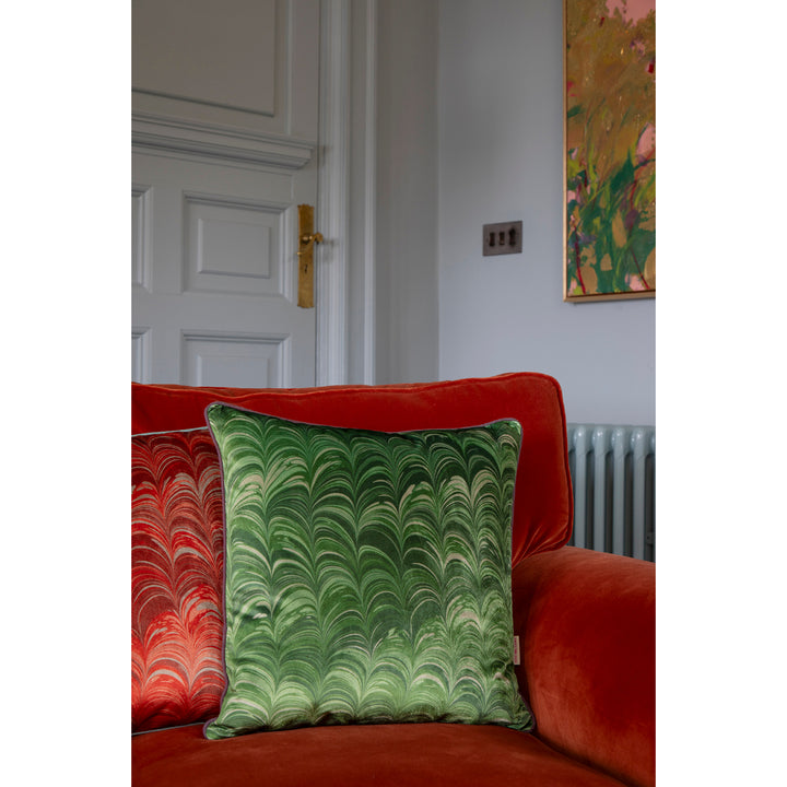 Green marbled pillow on a red couch with a pale blue background