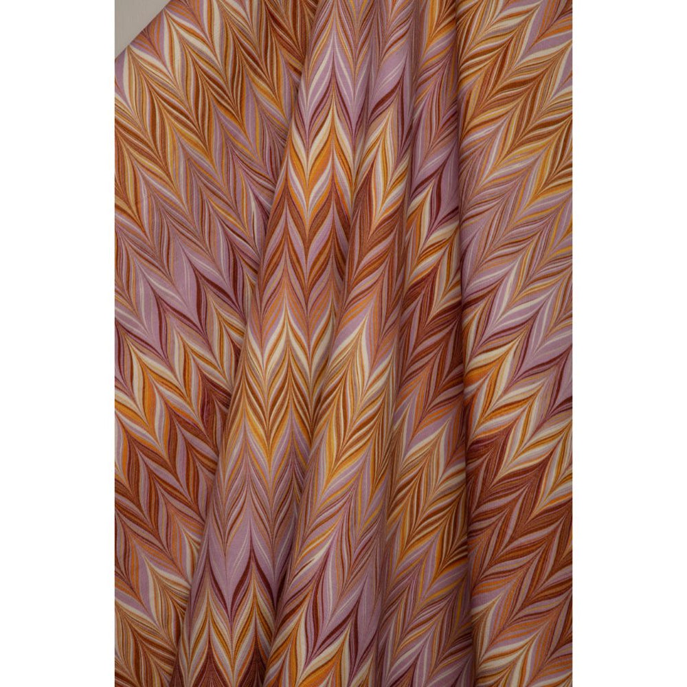A close-up of a draped fabric with a colorful chevron pattern in shades of orange, brown, pink, and cream.