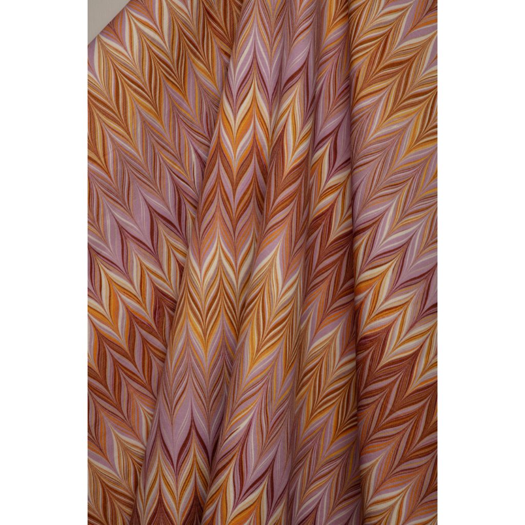 A close-up of a draped fabric with a colorful chevron pattern in shades of orange, brown, pink, and cream.