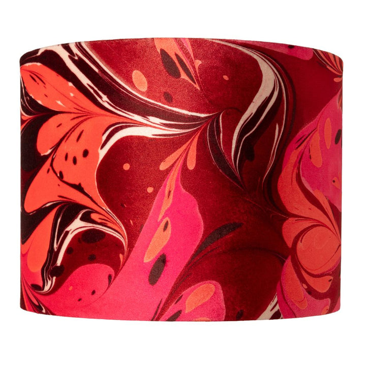 A drum lampshade featuring an abstract marbled pattern in vibrant shades of red, pink, and orange with white veining, set against a plain white background