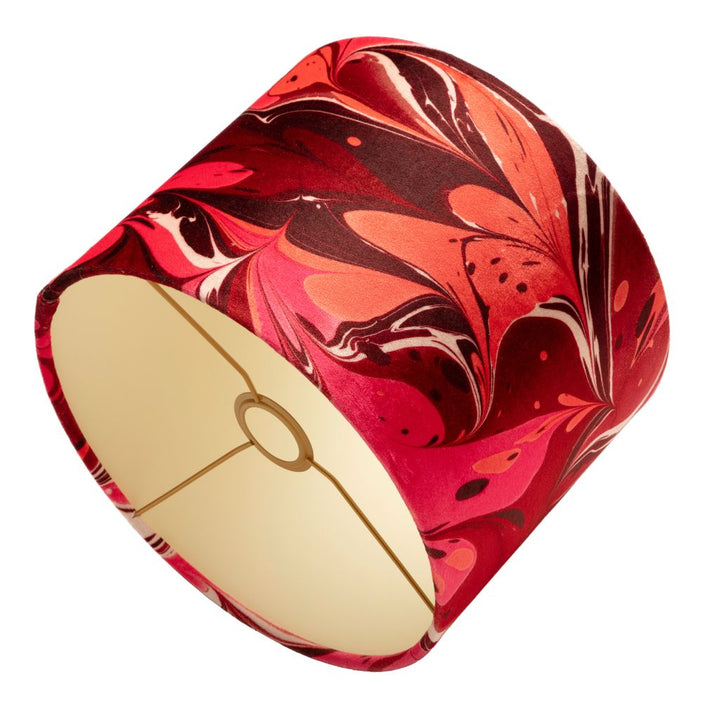 A drum lampshade featuring a vibrant red, pink, and orange marbled pattern on the exterior, with a cream coloured interior 