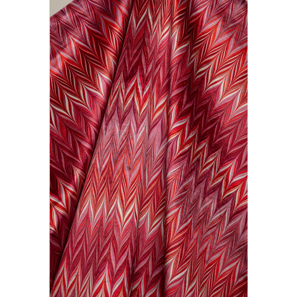 A close-up of draped fabric with a dense zigzag chevron pattern in red, pink, and white.