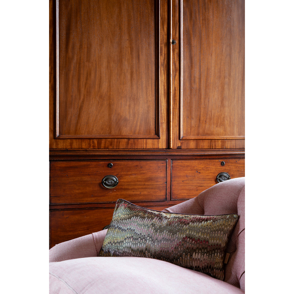 Wooden wardrobe with a pink chair and patterned pillow in a room setting