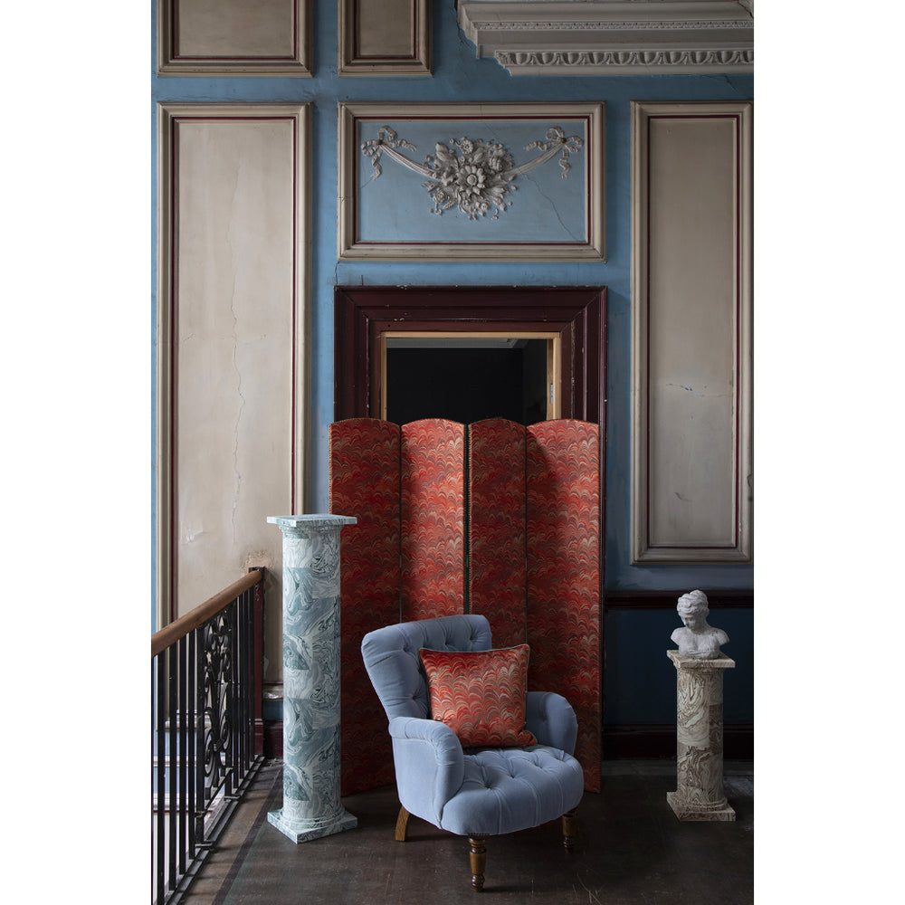 Decorative interior with a blue armchair, red cushion, and marble columns