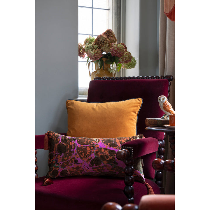Decorative pillows on a plush chair with a vase of flowers in the background