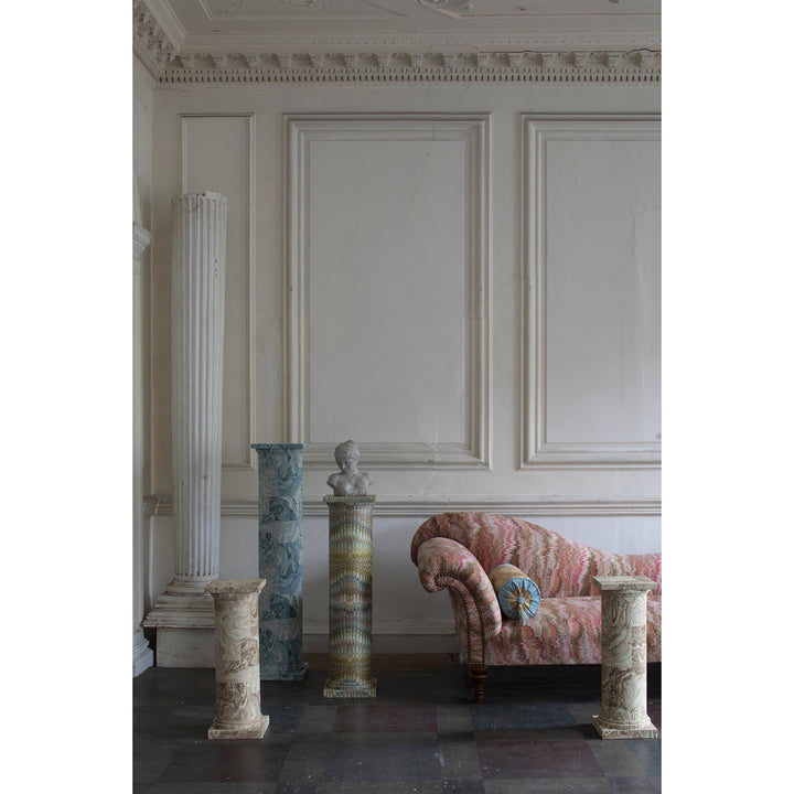 Decorative columns and a pink marbled pattern sofa in an elegant room with white panelled walls