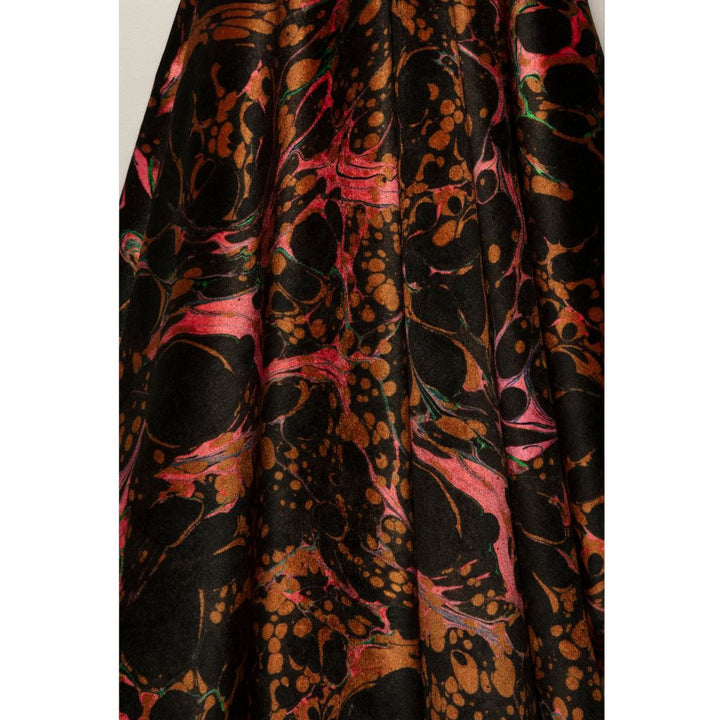 A close-up of a draped fabric with a black base featuring an abstract marbled pattern in metallic bronze-gold and vibrant pink.