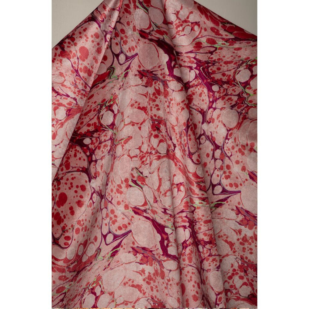 A draped piece of fabric featuring a marbled pattern in shades of pink, red, and purple on a light bubblegum pink base.