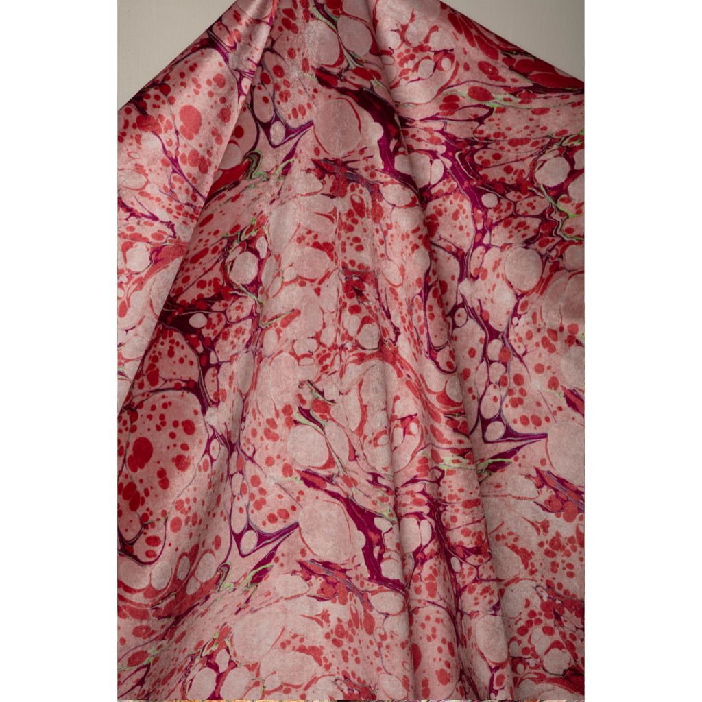 A draped piece of fabric featuring a marbled pattern in shades of pink, red, and purple on a light bubblegum pink base.