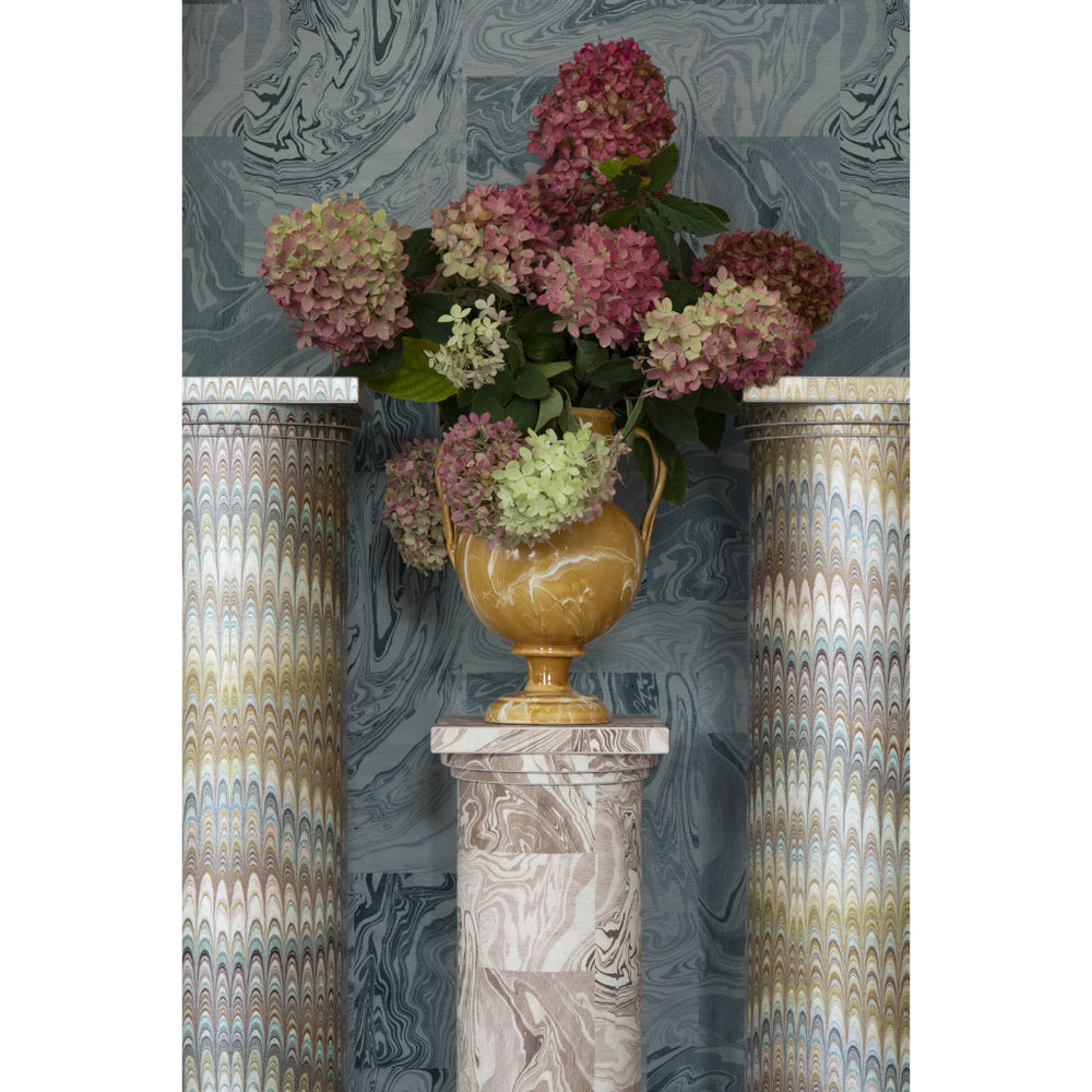 Decorative vase with flowers on a marble pedestal against a patterned wall.