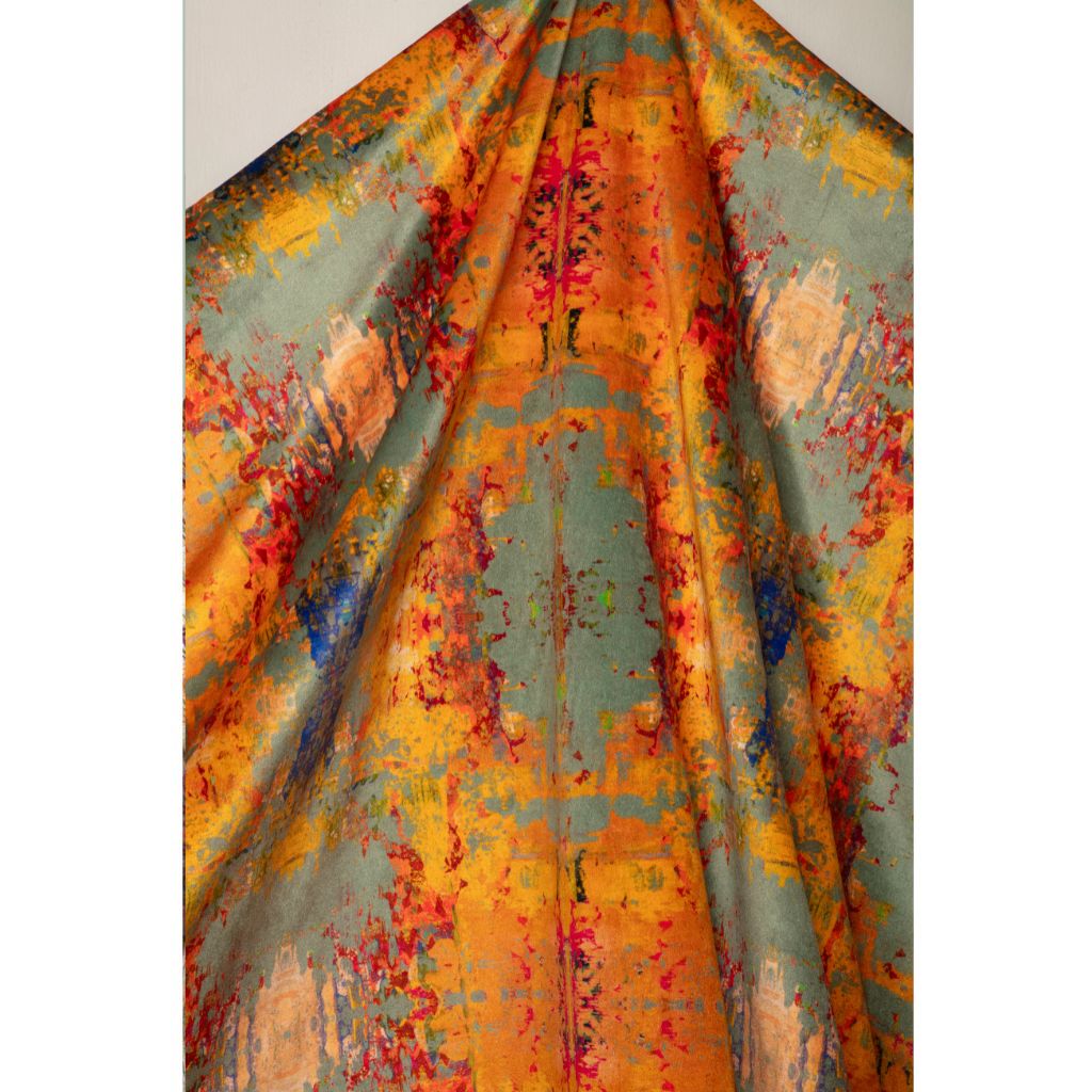 A draped piece of fabric with an abstract painterly pattern in orange, yellow, teal, red, and blue, shown against a plain light gray background.