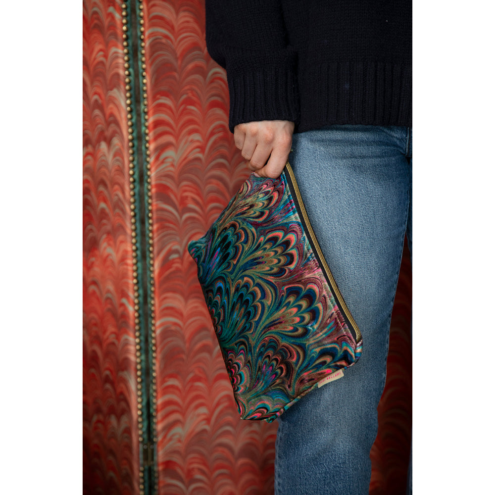 Marbled patterned clutch held by a person with a red and gold patterned background