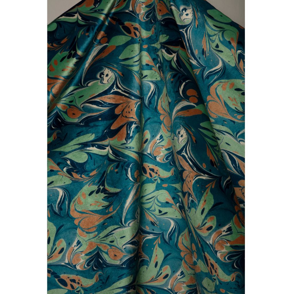 A draped piece of fabric featuring a marbled abstract pattern in teal, sage green, rust orange, and cream swirls.
