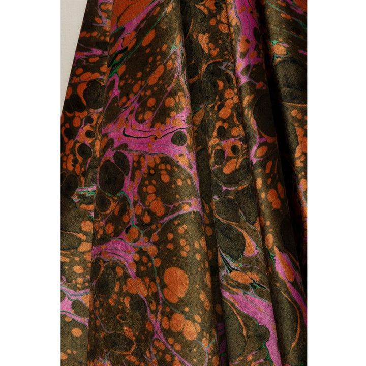 A close-up of draped fabric with an abstract marbled pattern in dark brown, orange, black, and bright pink.