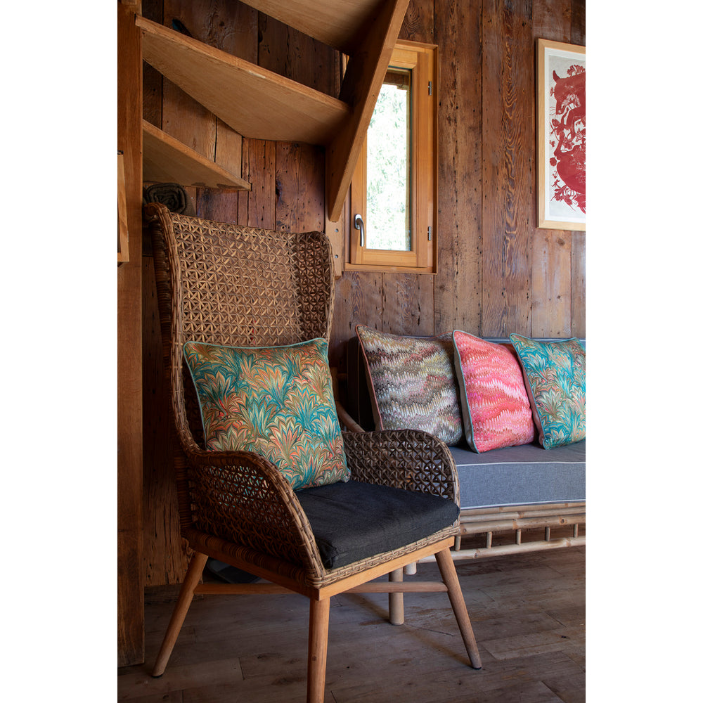 Wicker chair with colorful cushions in a rustic wooden room.
