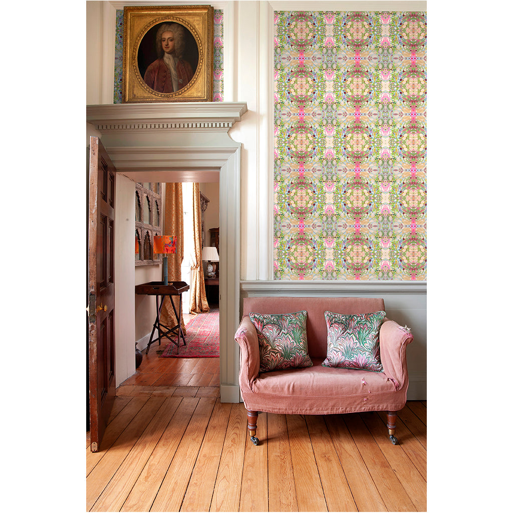 A room with beige ripple wallpaper featuring intricate designs in green, pink, and blue shades. The room includes a pink sofa and matching cushions, a wooden floor, and a painting on the wall.